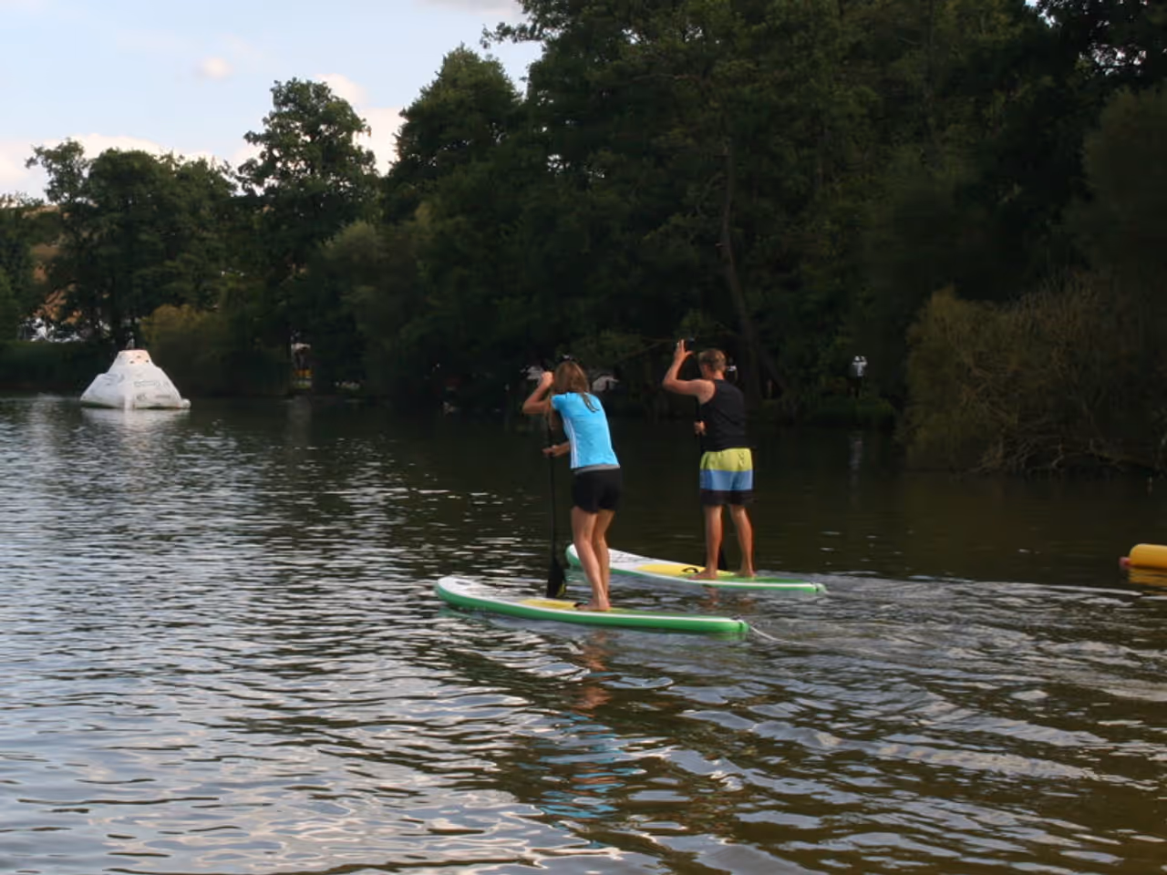 Gederner See — Paddler auf dem Wasser vor dem bewaldeten Ufer